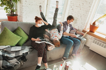 Caucasian famiy in face masks and gloves isolated at home with coronavirus respiratory symptoms...