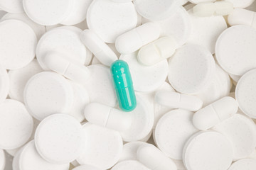 a single green pill between a lot of white pills