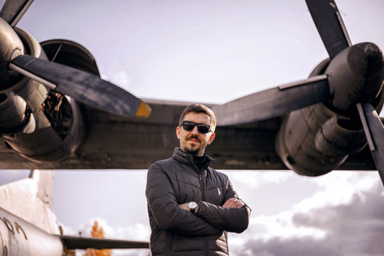 Young handsome man is standing near the plane.