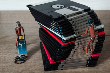 two small handmade human figures from resistors demonstrate advantages of modern flash storage versus old fashioned 3.5 inch diskettes
