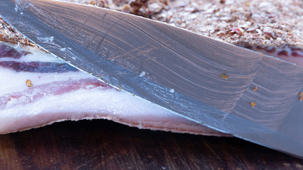 pork belly on wood board, knife in the foreground produced in calabria