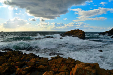 Stormy sea and waves are breaking on the rocks near the coastline