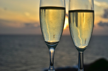 Two glasses of white wine with sunset on background