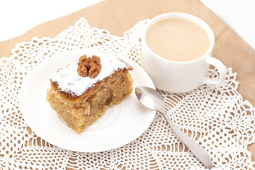 Sweet semolina pie on a white plate, a cup of tea with milk or coffee.