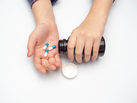 woman's hand holding blue and white tablets. self-medication during coronavirus