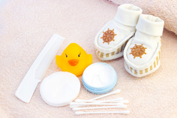Fototapeta na wymiar baby hygiene and bath items, shampoo bottle, baby soap, towel, yellow duck rubber toy, cotton pads and ear sticks, comb.