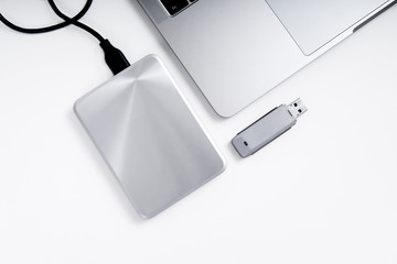 Portable hdd connected to a laptop and a usb flash drive on a grey background, flat lay. Data...