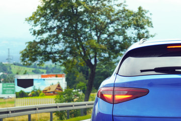 Fototapeta premium Led tail light of a blue car, luxury. A blue car behind a country road. Traffic outside the city.