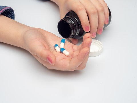 woman's hand holding blue and white tablets. self-medication during coronavirus