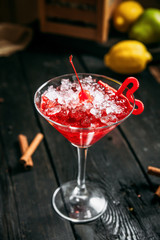 Fresh sweet red cosmopolitan cocktail in glass with crushed ice on the dark wooden background, side view