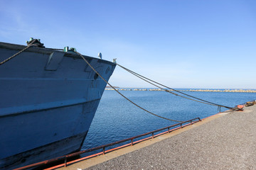 Old navy ship bow near the pier with the sea on the background