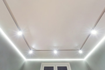 suspended ceiling with halogen spots lamps and drywall construction in empty room in apartment or house. Stretch ceiling white and complex shape.