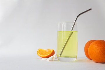 Vitamin C soluble effervescent tablets in a glass of water with a stainless straw. Orange. The drink enhances immunity and resistance to viruses.