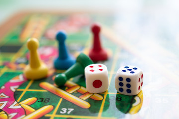 Colorful, bright game chips stand on a game Board with playing cubes: the concept of Board games, the background, games at home, a place for text