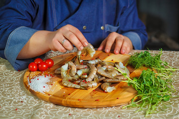 chef cooks tiger shrimps. Portrait. Funny photo. Dish with tiger shrimps, lime and tomatoes.