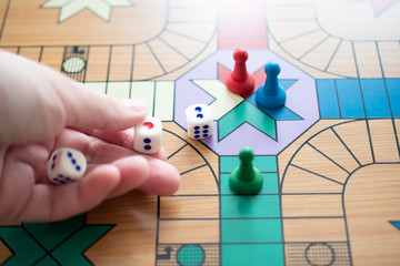 The hand throws the dice on the game Board, on which there are colorful, bright game chips: the...