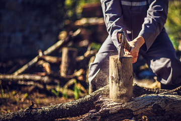 Man holding an industrial ax. Ax in hand. A strong man holds an ax in his hands against the background of chainsaws and firewood. Strong man lumberjack with an ax in his hand. Chainsaw close up.