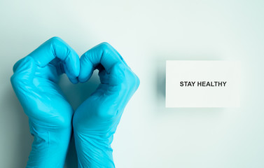stay home and healthy to prevent covid-19 spread campaign, text on paper with heart shape hands of...
