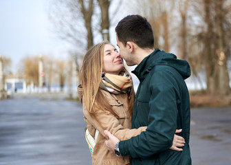 Young couple in love, standing, looking at each other, hugging, wearing casual clothes and jeans, on the rainy spring day. Romantic Valentines day celebration