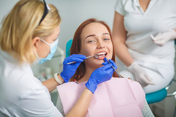 Young beautiful woman with beautiful white teeth sitting on a dental chair. Portrait of a woman with toothy smile sitting during examination at the dental office