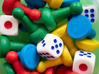 Multi-colored playing chips and dice cubes are grouped together on a green background: the concept of Board games, entertainment, background, games at home for the whole family