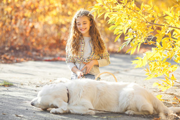 Portrait of young attractive blond girl with dog. Pet owner. Golden retriever and his owner at autumn background.