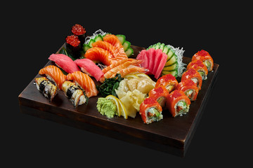 A large, diverse set with sushi, fresh sashimi and Philadelphia roll. Sushi with tuna, eel and salmon, shrimp, tuna, scallop and salmon sashimi and roll on a wooden tray. Photo for menu