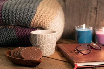 Cosy scene of coffee cup, biscuits, notebook and glasses with wooden background
