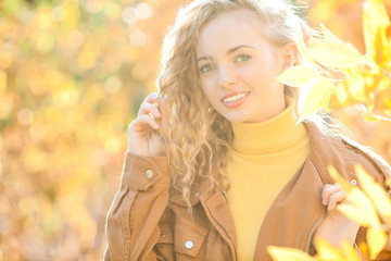 Close up portrait of beautiful blond girl on autumn background. Stylish young lady in park. Beautiful blond girl outdoors.