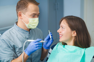 The girl is sitting in a chair at the dentist's appointment. Dental treatment. The dentist examines the patient's teeth. Teeth checkup at dentist's office.