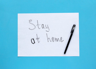 STAY AT HOME written on white sheet on blue background. Coronavirus concept pandemic Covid -19 prevention.