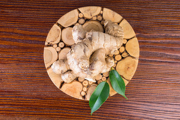 Ginger root with leaves on wooden background