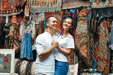 Fototapeta na wymiar Couple in love walks and hugs at the Eastern carpet market. A man and a woman choose a Turkish carpet