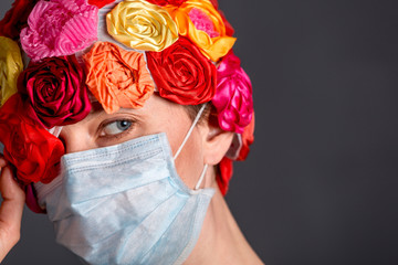 Woman with medical mask wearing artificial flower hat isolated over grey background. copy space