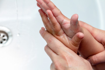 woman helps children wash hands under the tap close-up