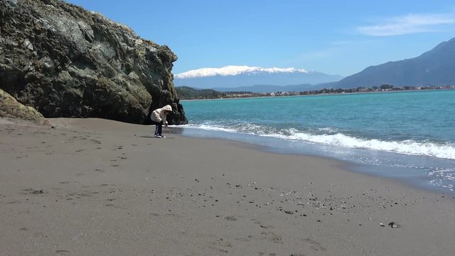 Karatas beach, Fethiye, Turkey - 3d of April 2020: 4K Sea view and a child drawing on sand with a stick
