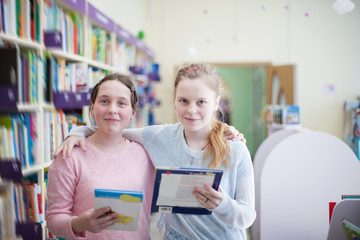 girls  choosing   book in   library.