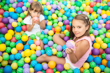 Fototapeta na wymiar Cheerful children smiling and playing in playroom with plastic balls. Hands raised up and holding toys