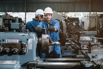 Engineer men wearing uniform safety workers perform maintenance in factory working machine lathe metal.