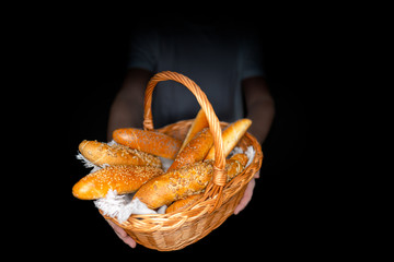 Man hold Fresh rolls in basket on dark background. Poppy seed roll and sesame seed roll. Typical popular czech breakfast rolls or buns.