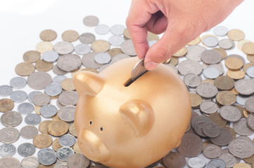 Inserting a coin into a gold piggy bank. Making savings concept.