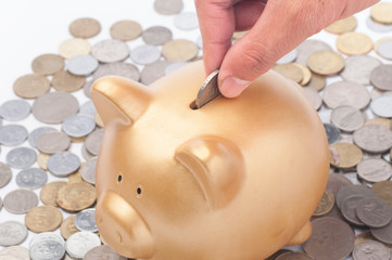 Inserting a coin into a gold piggy bank. Making savings concept.