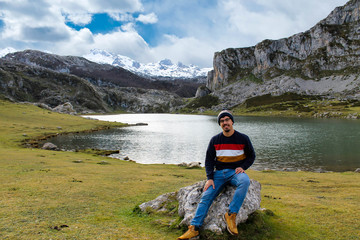 Boy sitting front on a rock, looking at the views of the lake and the mountain