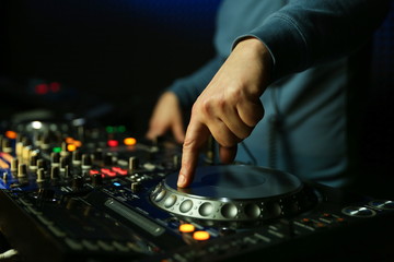dj is mixing tracks at party in night club. disc jockey playing music on the modern turntable close up. 