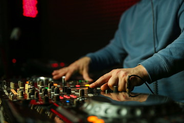dj is mixing tracks at party in night club. disc jockey playing music on the modern turntable close...