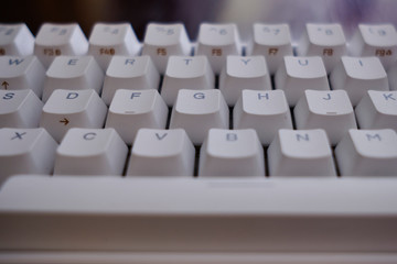 Close and front view of a white mechanical keyboard focused in keys D F G H J