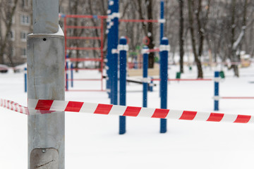 Begining of a quarantine of a coronavirus covid-19 in Moscow. Empty closed sports ground covered with snow and blocked by a barrier tape.