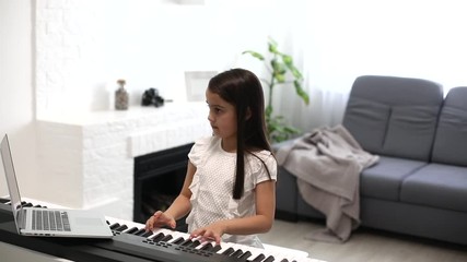 Scene of piano lessons online training or E-class learning while Coronavirus spread out or covid-19 crisis situation, little girl studying from home.