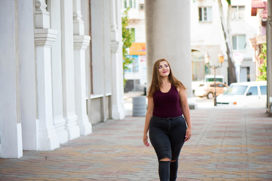 Pretty young woman walking on the city street. Casual fashion, plus size model. xxl women on nature.