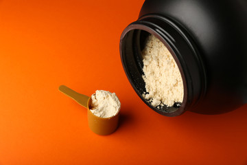 jar and measuring cup with gainer on an orange background. protein powder on orange background top view with copy space. 